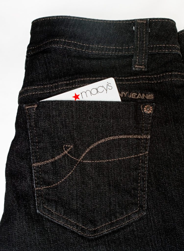 Pair of DKNY designer jeans with a Macy's credit card in the back pocket