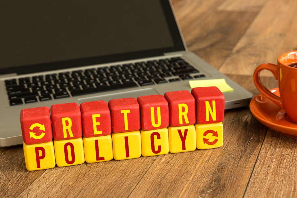 Return Policy written on a wooden cube in a office desk